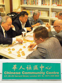 中国式チェスを楽しむセンター利用者たちとコミュニティセンターの看板