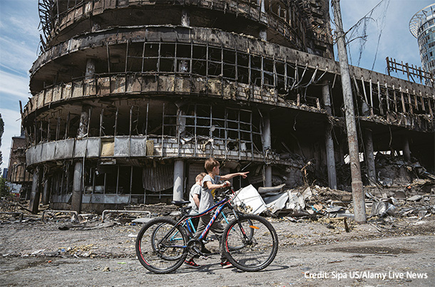 5月24日、ウクライナの首都キーウで爆撃を受けた建物の前を通る子どもたち