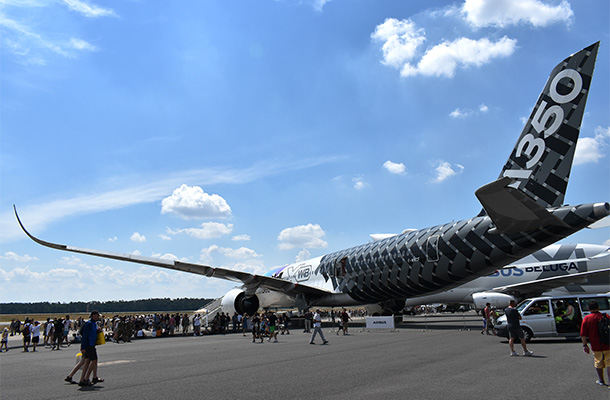 エアバスの最新鋭旅客機A350XWBと、翼の下で涼を取る人々