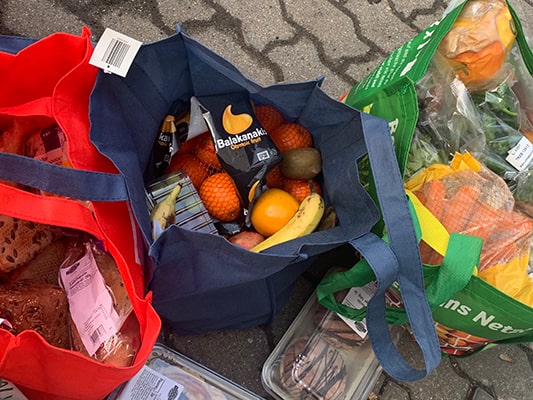 袋いっぱいに詰められたフルーツ、野菜、パンなど
