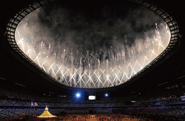 東京五輪の開会式で聖火（左下）がともされ、打ち上がる花火＝7月23日、東京・国立競技場「時事（JIJI）」
